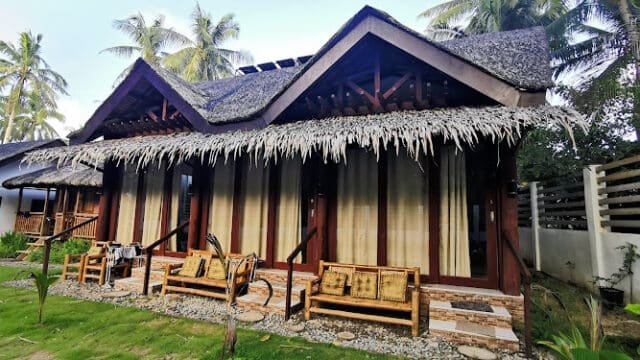 A tropical Siargao bungalow with bamboo furniture and palm trees in the background.