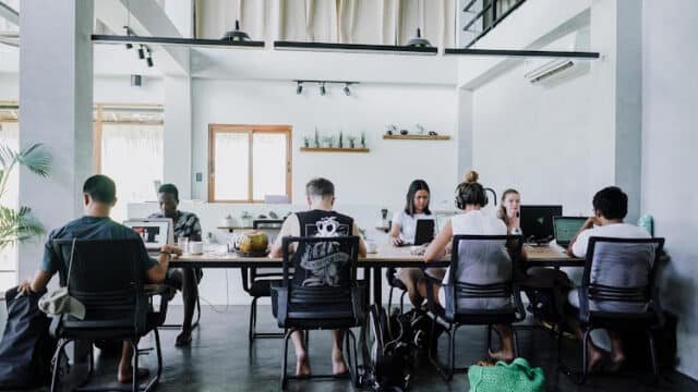 People working on laptops at a long table in a bright, modern Siargao office space.