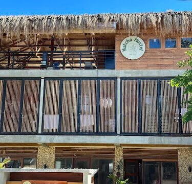 A two-story building with wooden accents in Siargao, featuring a sign reading Matcha Hostel on the upper level.