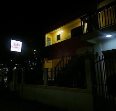 A building with a lit sign and yellow lights on the upper floor in Siargao, photographed at night.