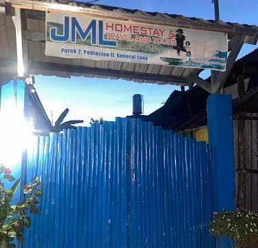 Blue gate under a sign that reads JMI Homestay & Travel and Tours, welcoming guests to Siargao at an outdoor entrance.