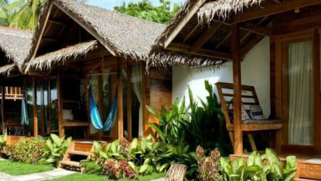Wooden bungalows with thatched roofs, hammocks, and lush green plants in front capture the relaxed vibe of Siargao.