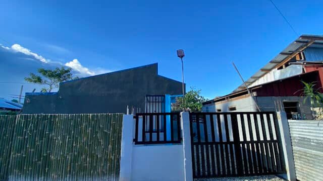A modern black gate and fence in front of a house, set against the clear blue Siargao sky above.