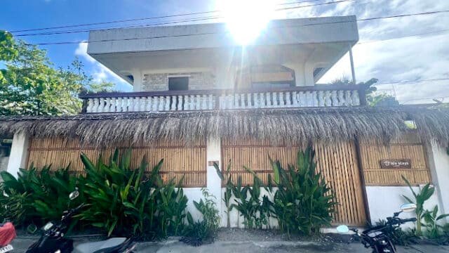 Two motorcycles parked in front of a bamboo-fenced building with plants, under Siargao's bright sunlight and blue sky.