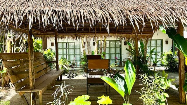 Thatched-roof gazebo with wooden benches, surrounded by lush tropical plants and greenery in scenic Siargao.