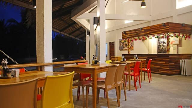 Modern open-air restaurant in Siargao with colorful chairs, wooden tables, and festive garlands on the counter.
