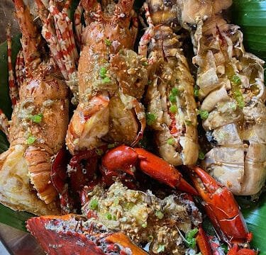 Lobsters and crab cooked with garlic and spices, served on banana leaves—an authentic Siargao coastal delight.