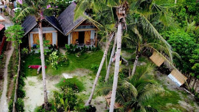 Aerial view of two small cottages in Siargao, surrounded by tropical trees and lush greenery.