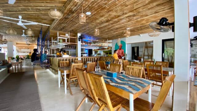 Siargao restaurant with wooden tables and chairs, bamboo ceiling, and a bar area in a bright, airy setting.