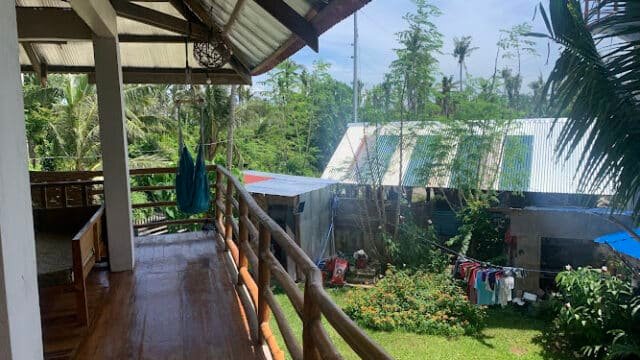 View from a wooden balcony in Siargao, overlooking a green garden with laundry hanging and a hammock on the porch.