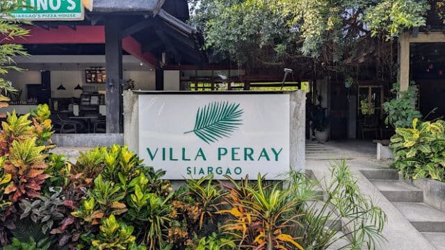Entrance of Villa Peray Siargao, marked by a welcoming sign and lush Siargao greenery in front of the building.