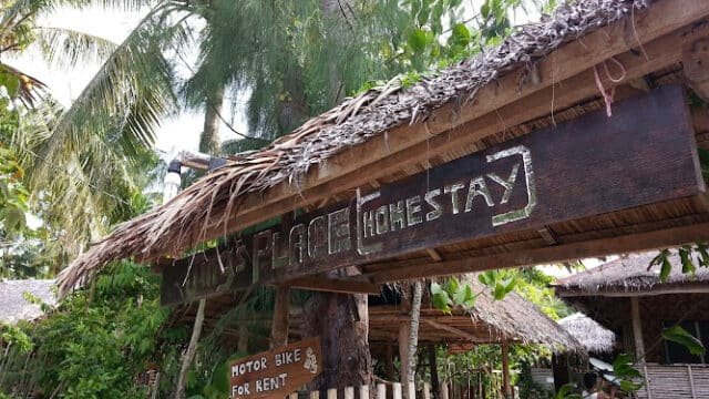 A rustic wooden sign reads Jungle Place Homestay under a thatched roof, surrounded by Siargao’s lush tropical trees.
