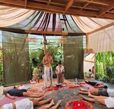People lying on yoga mats in a tropical Siargao pavilion, with two instructors standing near a flower mandala.