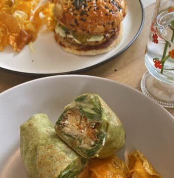 A chicken wrap and chips in the foreground, with a burger and chips on a plate in the background, served Siargao style.