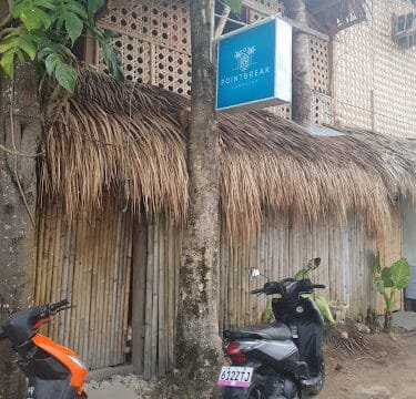 Two motorbikes parked outside a bamboo and thatch building with a blue Pointbreak sign hanging above in Siargao.