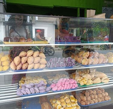 A glass display case filled with assorted colorful pastries and bread inside a cozy Siargao bakery.