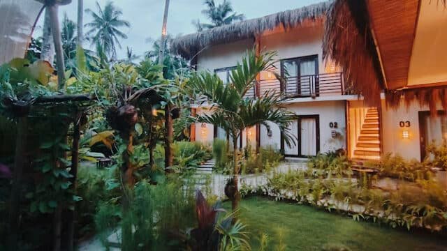 Tropical garden courtyard with lush plants and modern two-story buildings at dusk in picturesque Siargao.