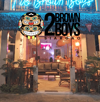 Two Brown Boys Siargao restaurant exterior with neon sign, open glass doors, and a vibrant Siargao nightlife vibe.