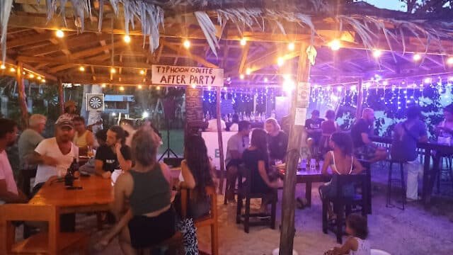 People gather under string lights at a Siargao beach bar for a Typhoon Odette After Party in the evening.
