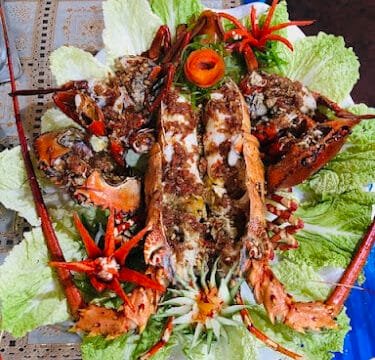 A beautifully plated lobster dish with lettuce leaves, garnished with carved vegetables and herbs, inspired by Siargao's fresh flavors.
