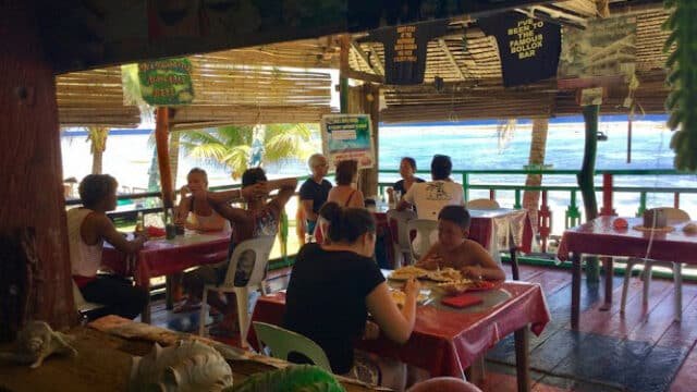 People dining at a beachside Siargao restaurant with ocean views, red tablecloths, and a casual, relaxed atmosphere.
