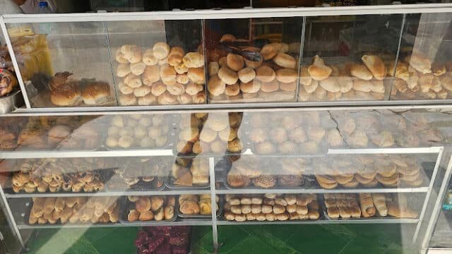 Glass display case filled with various bread rolls and pastries in a Siargao bakery.