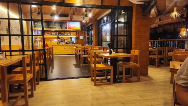 Cozy restaurant interior with wooden tables and chairs, warm lighting, and a visible bar area reflecting Siargao’s relaxed island vibe.