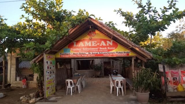 A rustic snack house in Siargao with a sign reading Lame-an and plastic chairs and tables outside.