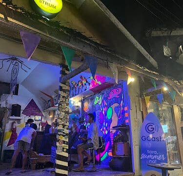 Colorful Siargao bar at night with neon lights, people inside, and bunting flags hanging outside the entrance.