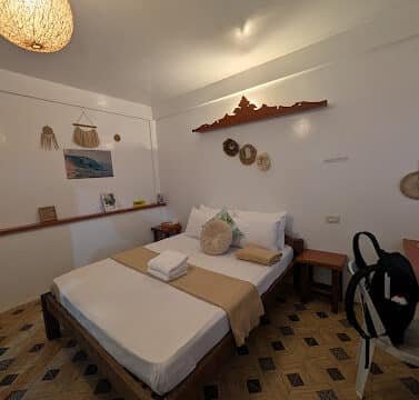 A cozy, well-lit Siargao bedroom with a double bed, woven decor, and a stunning patterned tile floor.