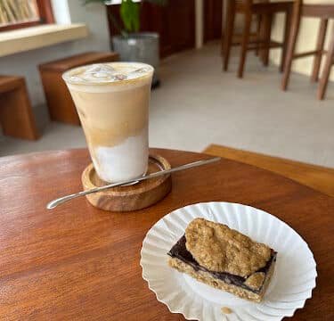 Iced latte and a chocolate oat bar on a wooden table in a cozy Siargao café setting.