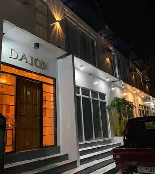 A modern white building named DAJON in Siargao is lit up at night, with steps leading to its entrance.