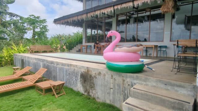 Inflatable floaties by a small pool next to a modern house with patio seating and wooden lounge chairs, evoking Siargao's relaxing vibes.