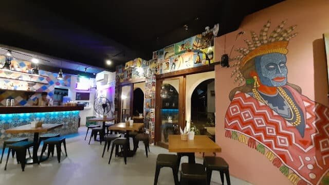 Colorful Siargao restaurant interior with wall art of a blue-faced figure in traditional attire; empty tables and chairs.