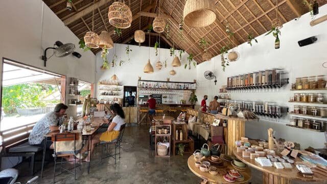 Cozy Siargao cafe with wooden decor, hanging lights, people working at tables, and jars lining the walls.