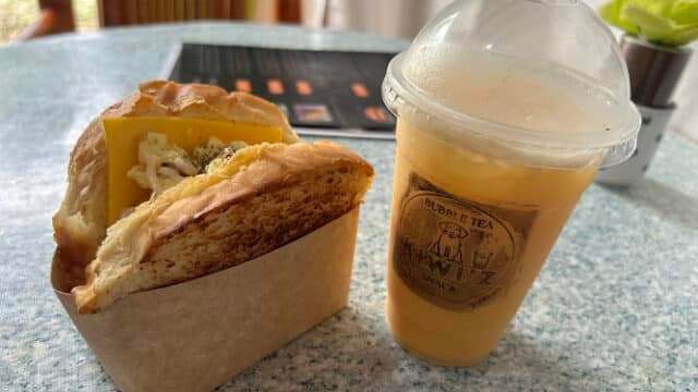 A sandwich with cheese and a cup of iced bubble tea on a table, capturing the laid-back vibes of Siargao.