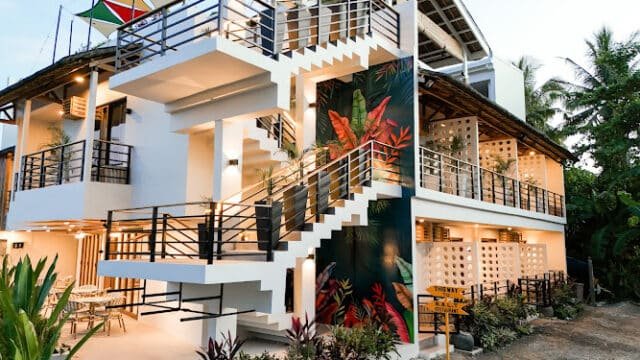 Modern two-story building with outdoor stairs, plants, and a colorful mural, surrounded by Siargao’s lush greenery.