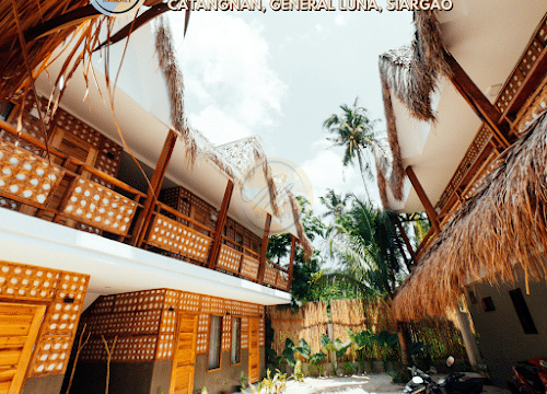 Courtyard view of M-Resort Siargao with native-style rooms, tropical plants, and a parked motorcycle in stunning Siargao.