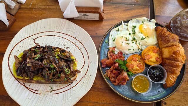 A Siargao breakfast spread with eggs, bacon, croissant, preserves, tomatoes, and toast topped with sautéed mushrooms.