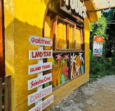 Yellow tour office in Siargao with painted flowers and signs for land tours, island tours, Sohoton Cove, Corregidor, and rentals.