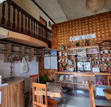 Cozy Siargao coffee shop interior with wooden furniture, warm lighting, and a COFFEE TIME sign on the wall.