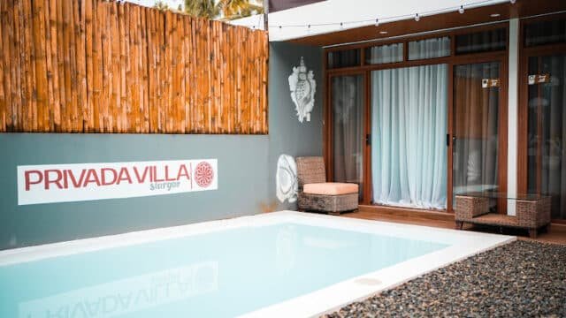 A small private Siargao villa pool with patio chairs, bamboo fence, and Privada Villa Siargao sign on the wall.